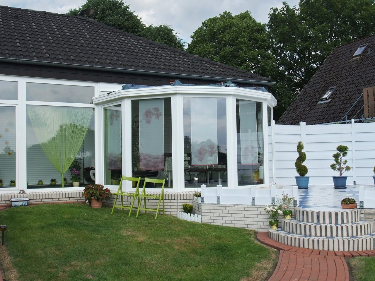 Weißer Wintergarten mit segmentiertem Grundriss und großen Glasflächen an einem Bungalow